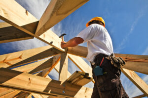 An El Paso home builder hammering wood beams.
